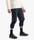 Person wearing dark shorts, leggings, and black shoes on a white background