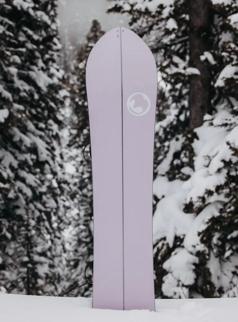 Purple snowboard with a logo against a snowy forest background