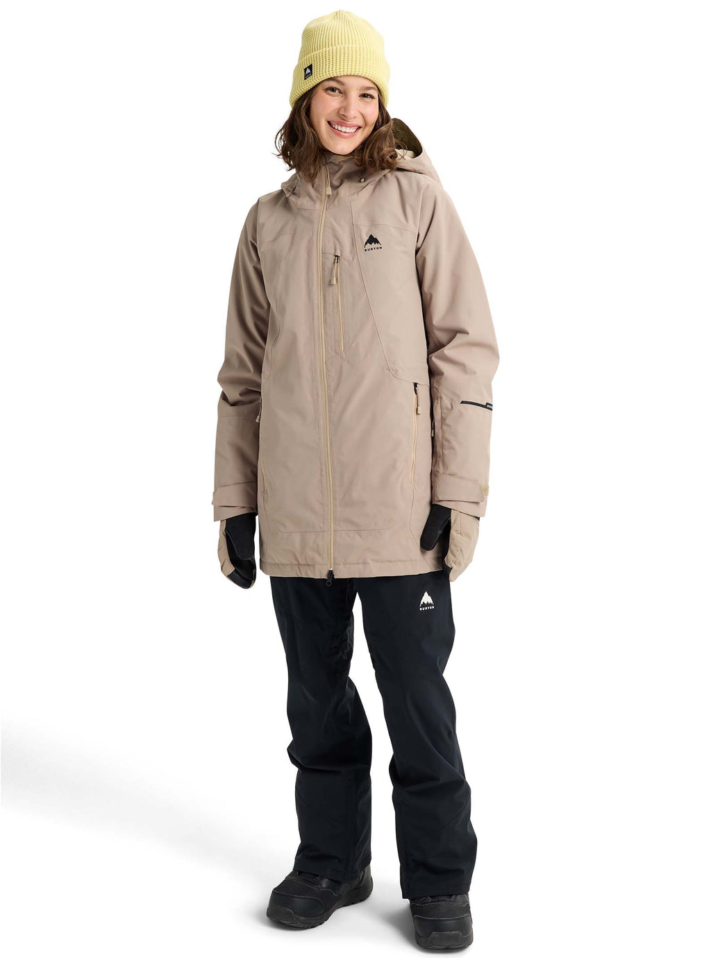 Person wearing a beige snow jacket and black pants on a white background