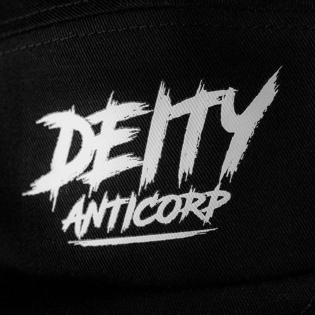 Close-up of a black baseball cap featuring a white embroidered graphic that reads 'DEITY ANTICORP' in a distressed, brush-stroke style.