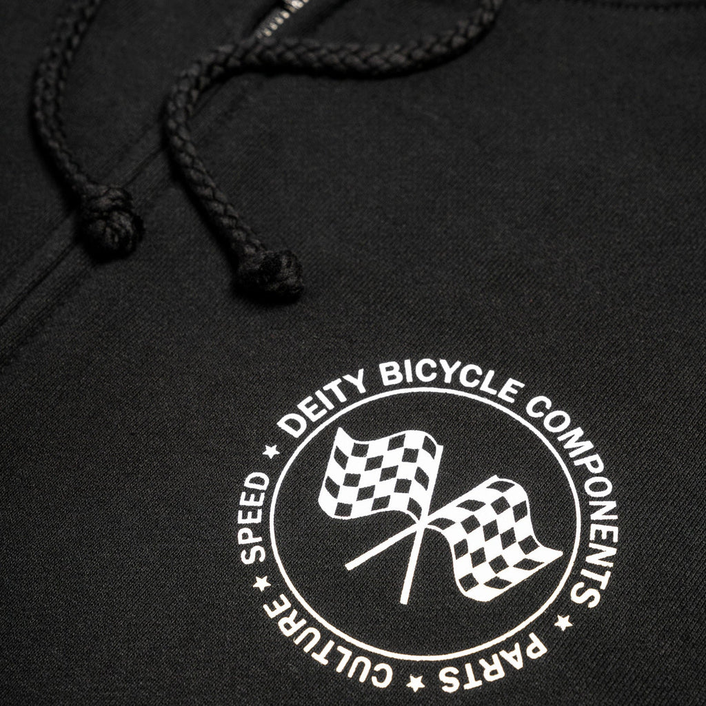 Close-up of a black hoodie with a white circular chest graphic featuring two checkered flags and the text 'DEITY BICYCLE COMPONENTS' and 'SPEED CULTURE PARTS'.
