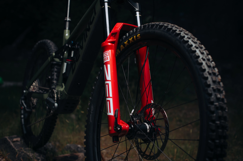 Close-up of a red mountain bike suspension fork with a dark background
