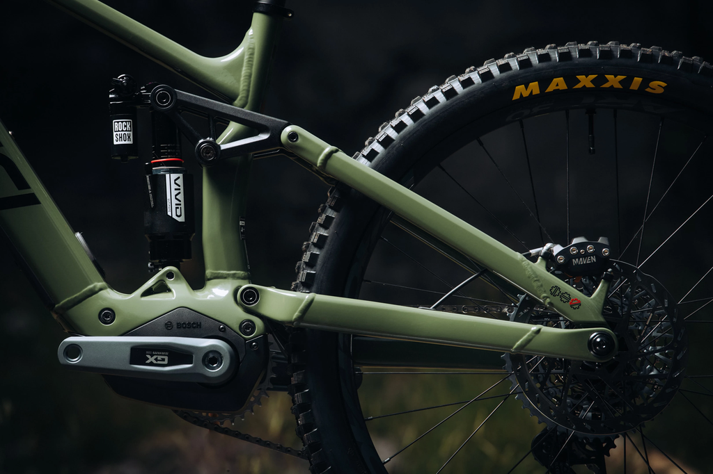 Close-up of a mountain bike with a focus on the suspension fork and wheel, featuring Maxxis tires.