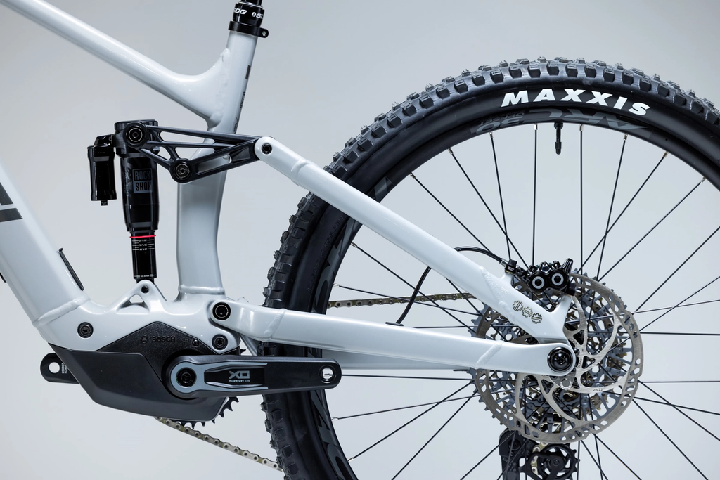 Close-up of a bicycle with a white frame and Maxxis tire on a gray background