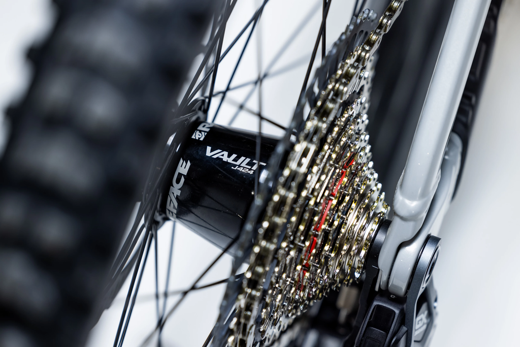 Close-up of a bicycle chain and gear system with a 'Vault' brand visible.