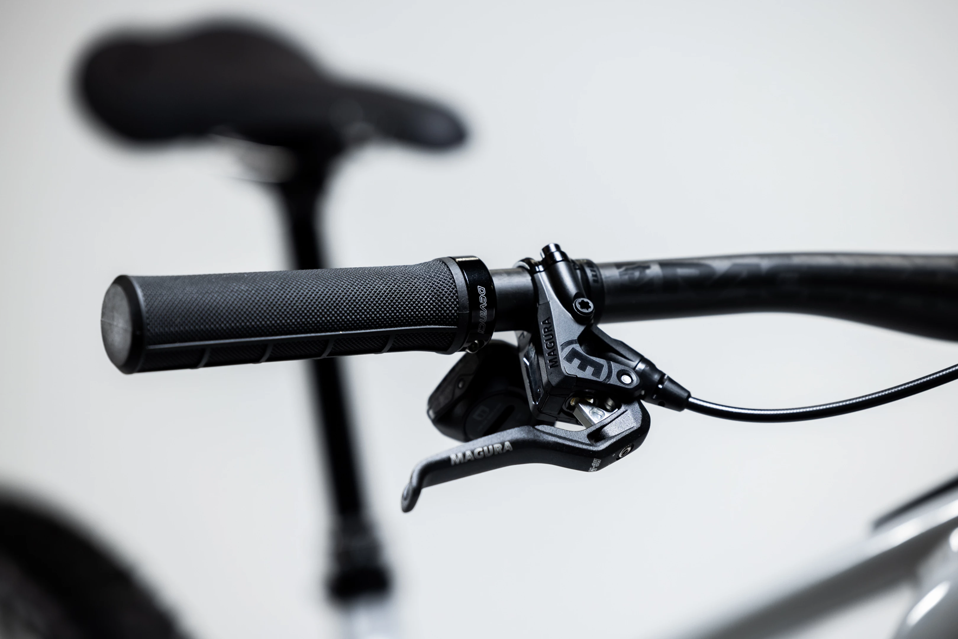 Close-up of a bicycle handlebar with black grips and brake levers on a blurred background