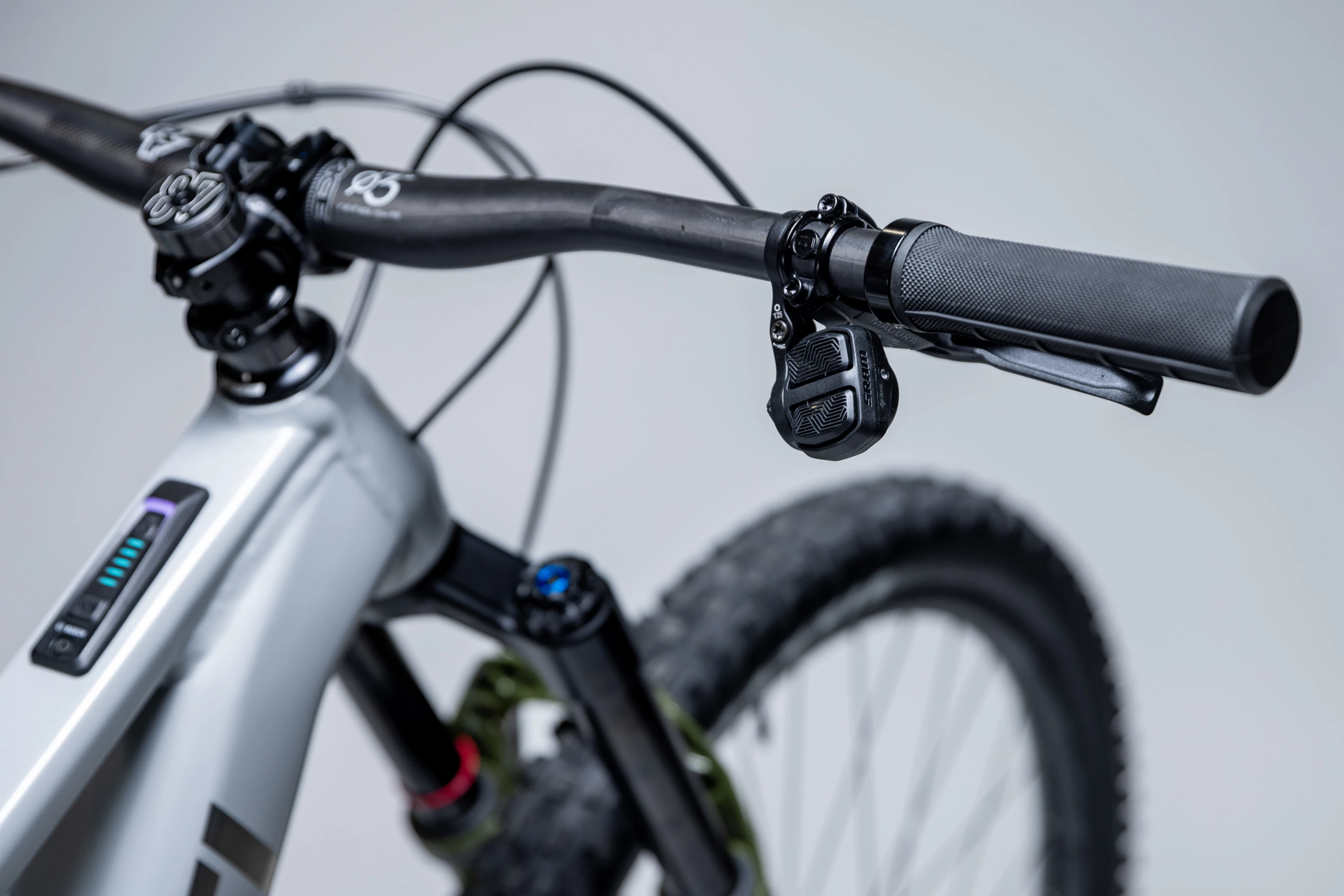 Close-up of a bicycle handlebar with control buttons on a gray background