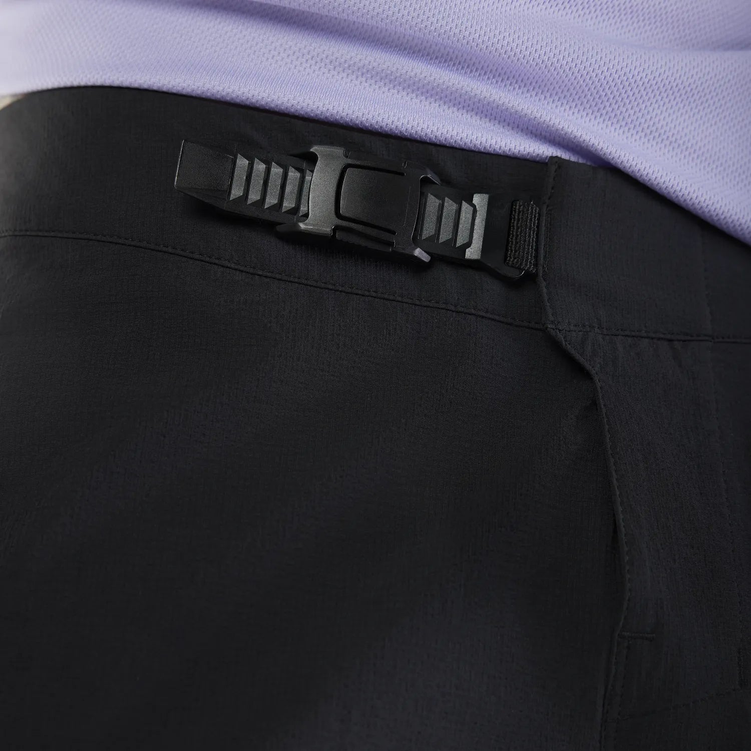 Close-up of black pants with a black belt and purple shirt.