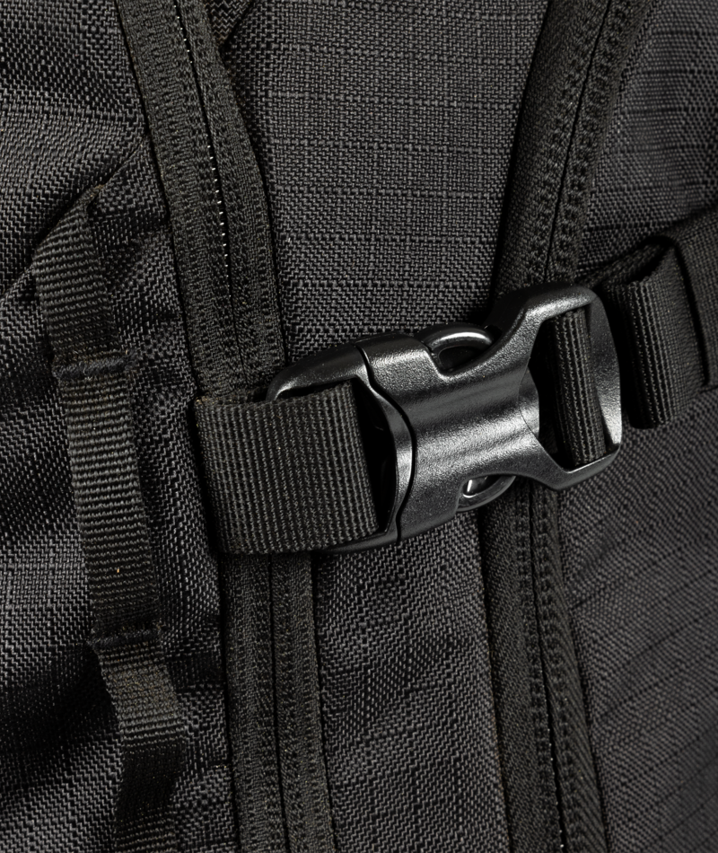 Close-up of a black backpack with a buckle on a textured fabric background