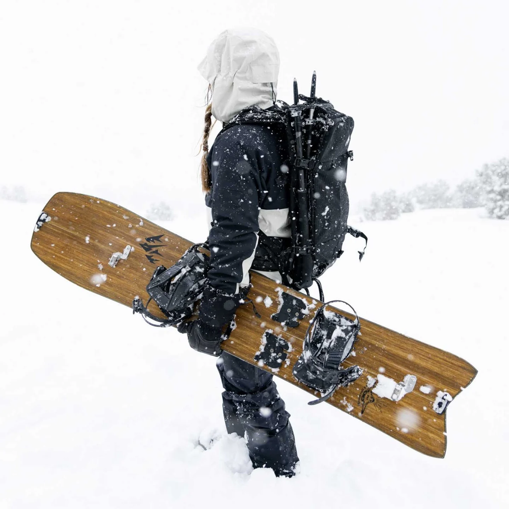 Person with a snowboard and backpack in a snowy landscape