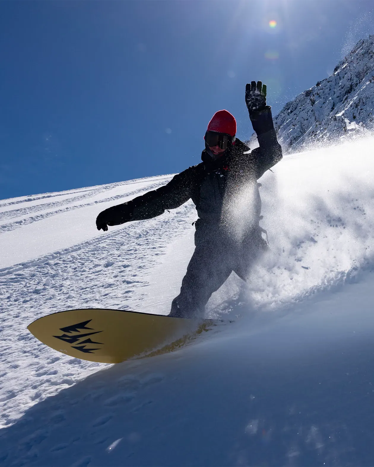 Person snowboarding down a snowy slope with a clear blue sky