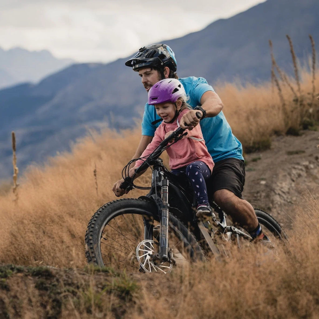 Man and child riding a mountain bike together with mountains in the background