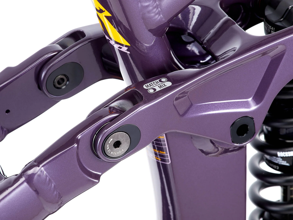 Close-up of a purple bicycle suspension system with visible branding on a white background