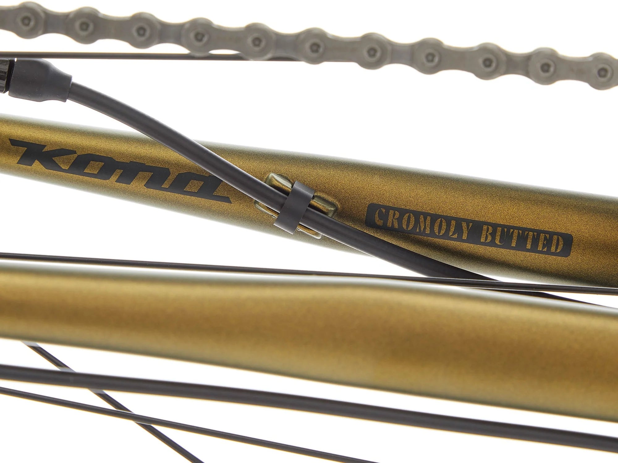 Close-up of a bicycle frame tube in a metallic gold finish with black text reading 'KONA' and 'CROMOLY BUTTED', alongside a black cable secured with a zip tie and part of the chain visible against a white background.