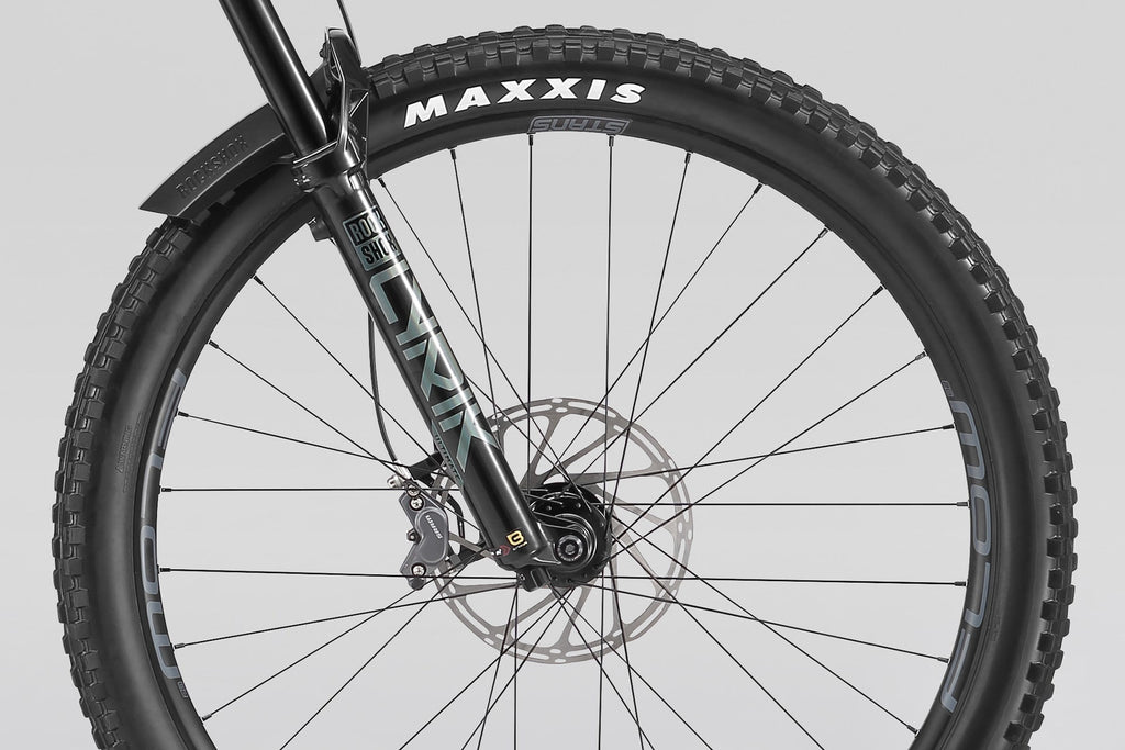 Close-up of a bicycle wheel with Maxxis tire on a gray background