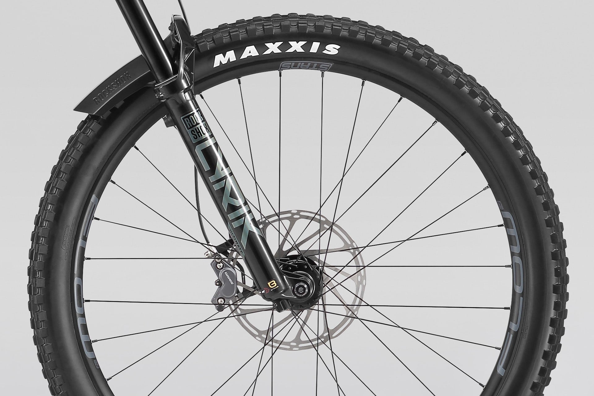 Close-up of a bicycle wheel with Maxxis tire on a gray background