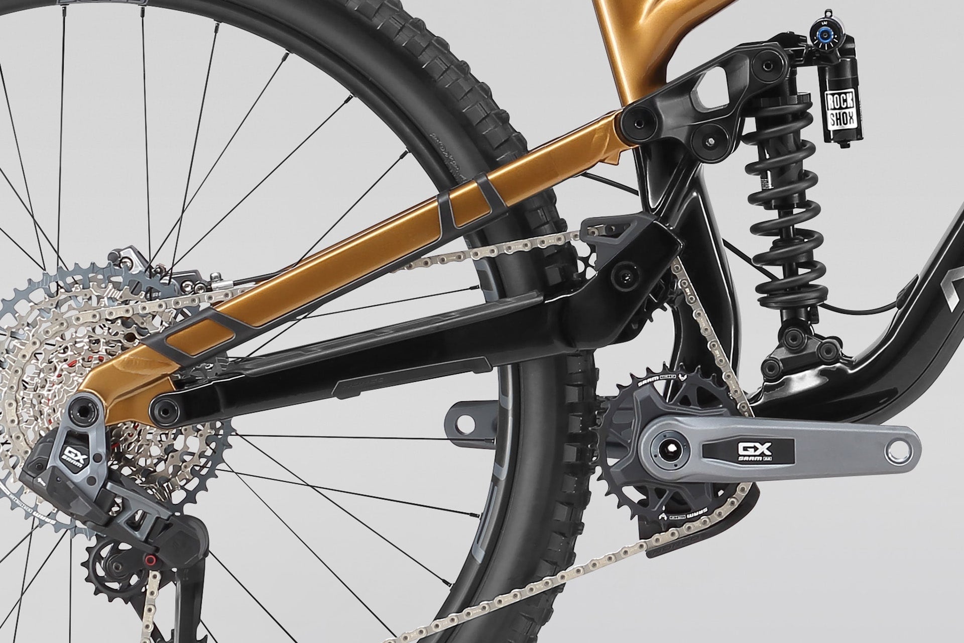 Close-up of a bicycle's gear system with a gold frame on a gray background