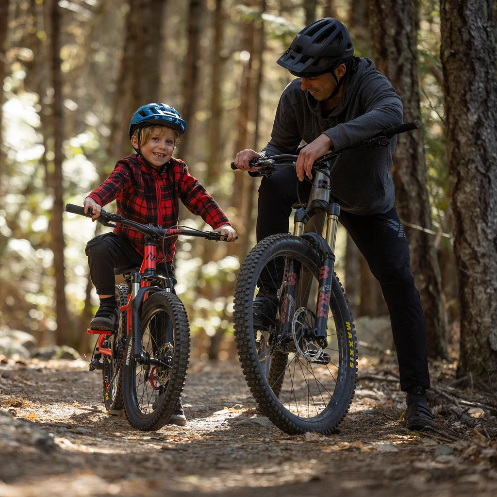 Man and child on mountain bikes in a forest setting