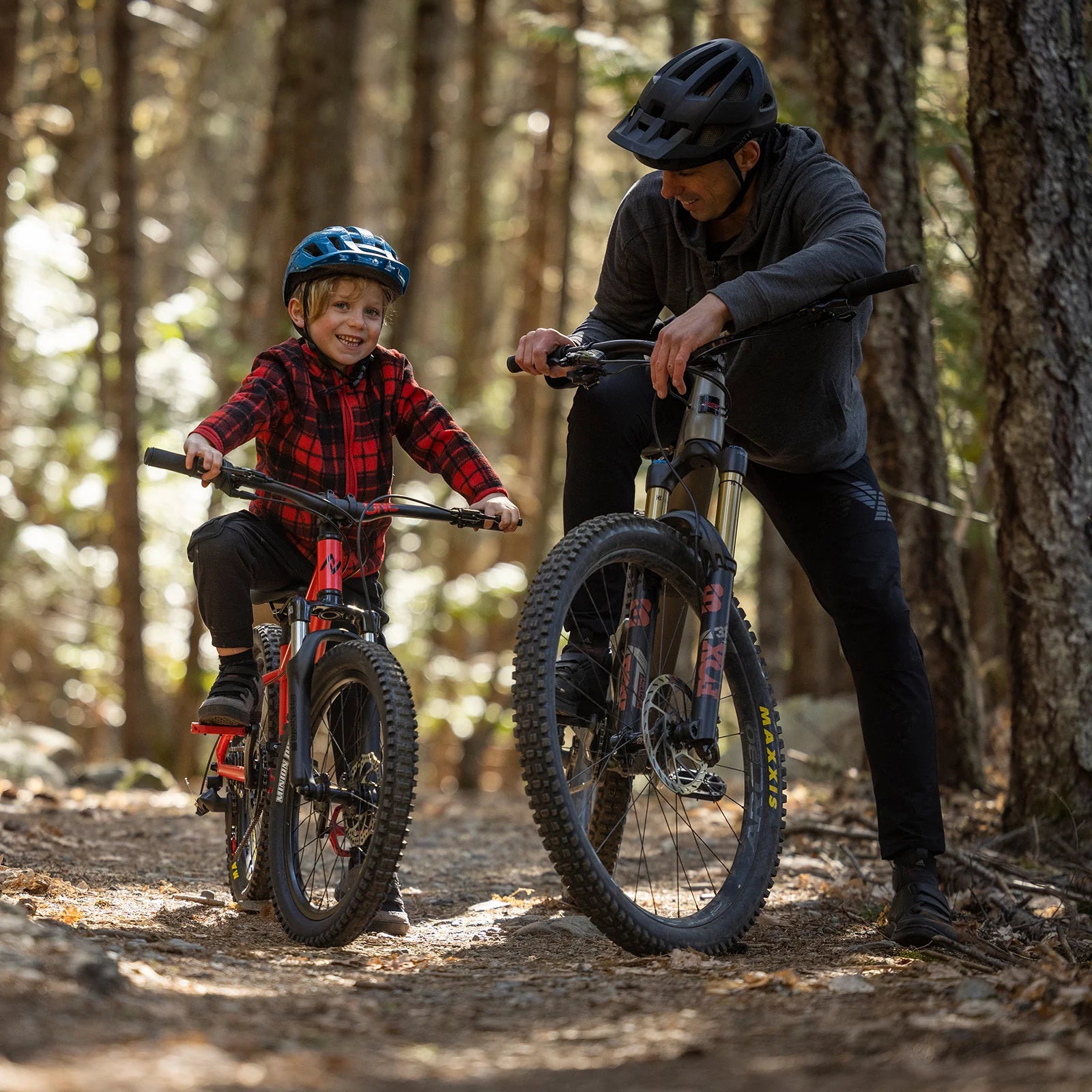 Man and child on mountain bikes in a forest setting