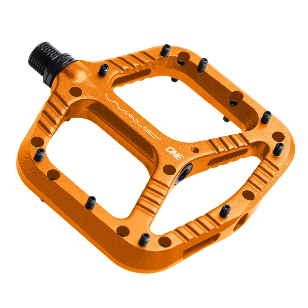 An orange bicycle pedal with black textured rubber platform pads and a black threaded spindle, shown on a plain white background.
