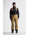Person wearing a black jacket and tan pants with a white background