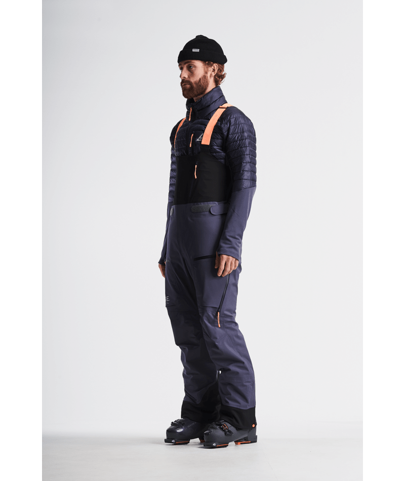 Man wearing a black and orange insulated jacket and pants on a white background