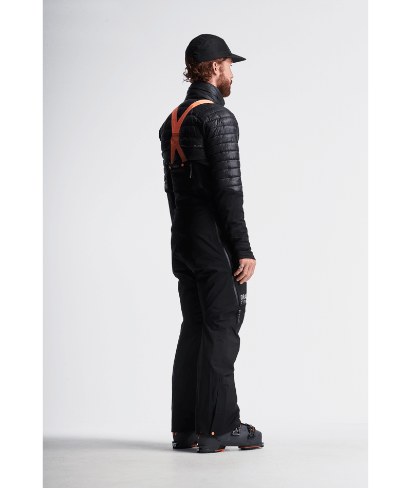 Person wearing a black outfit with suspenders on a white background