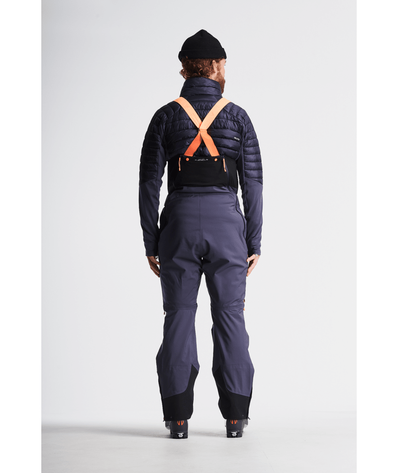 Person wearing a dark blue ski suit with orange accents on a light gray background