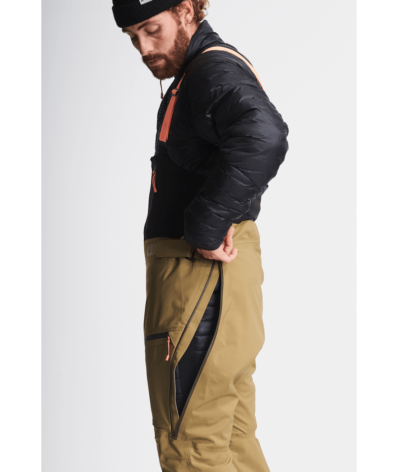 Man wearing a black jacket and green pants on a light gray background