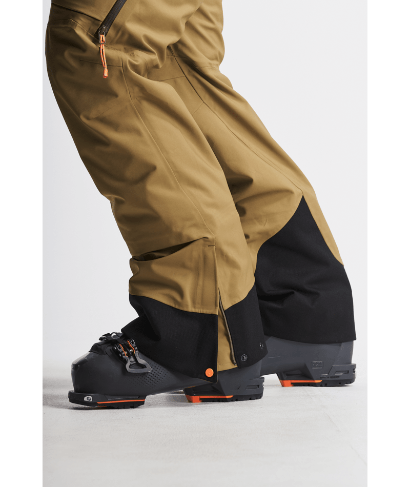 Brown and black ski pants with orange accents on a light gray background