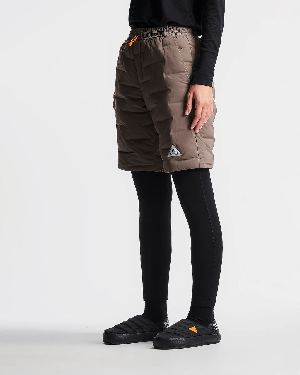 Person wearing brown cargo shorts with a logo on a white background