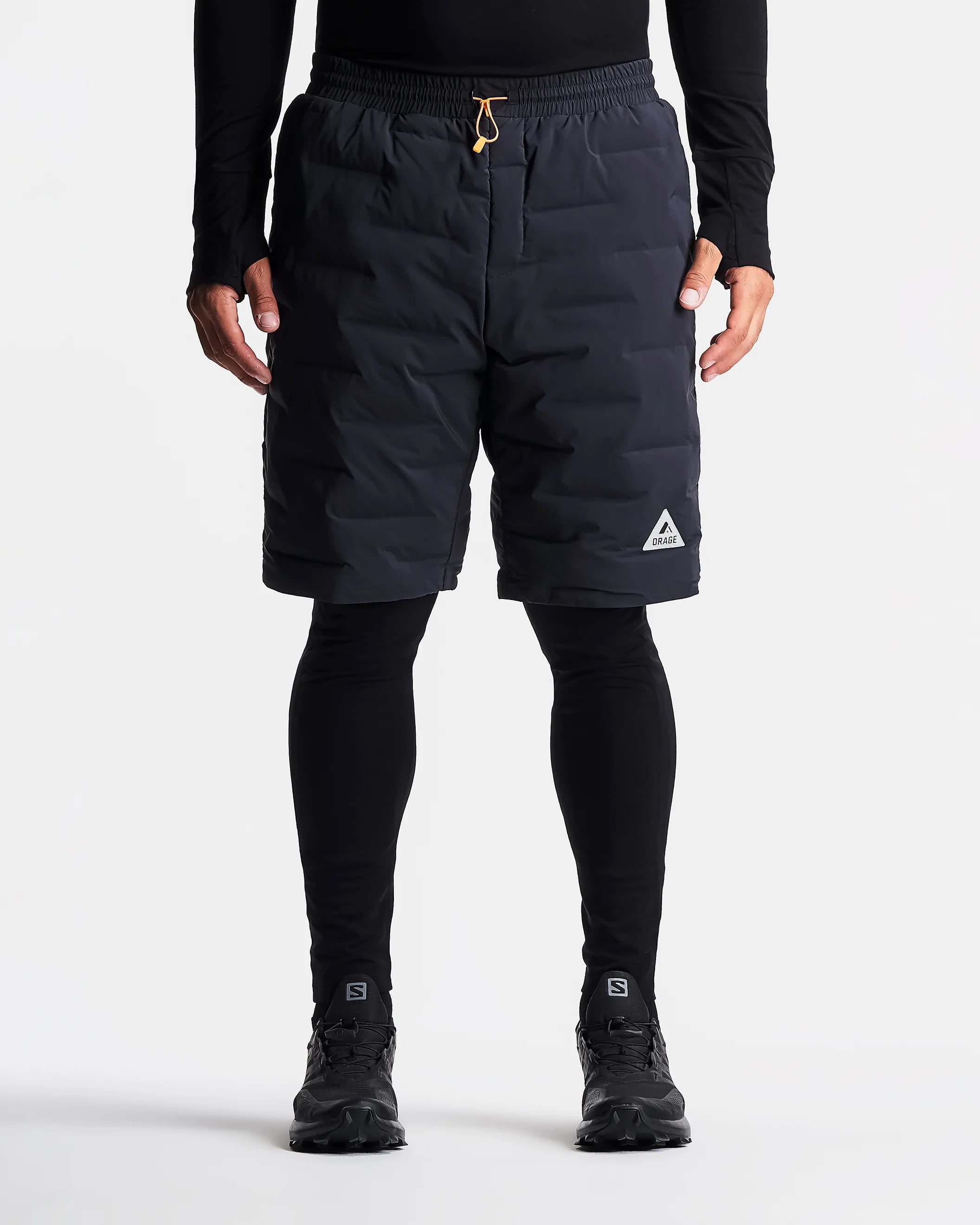 Person wearing black shorts with a brand logo on a white background