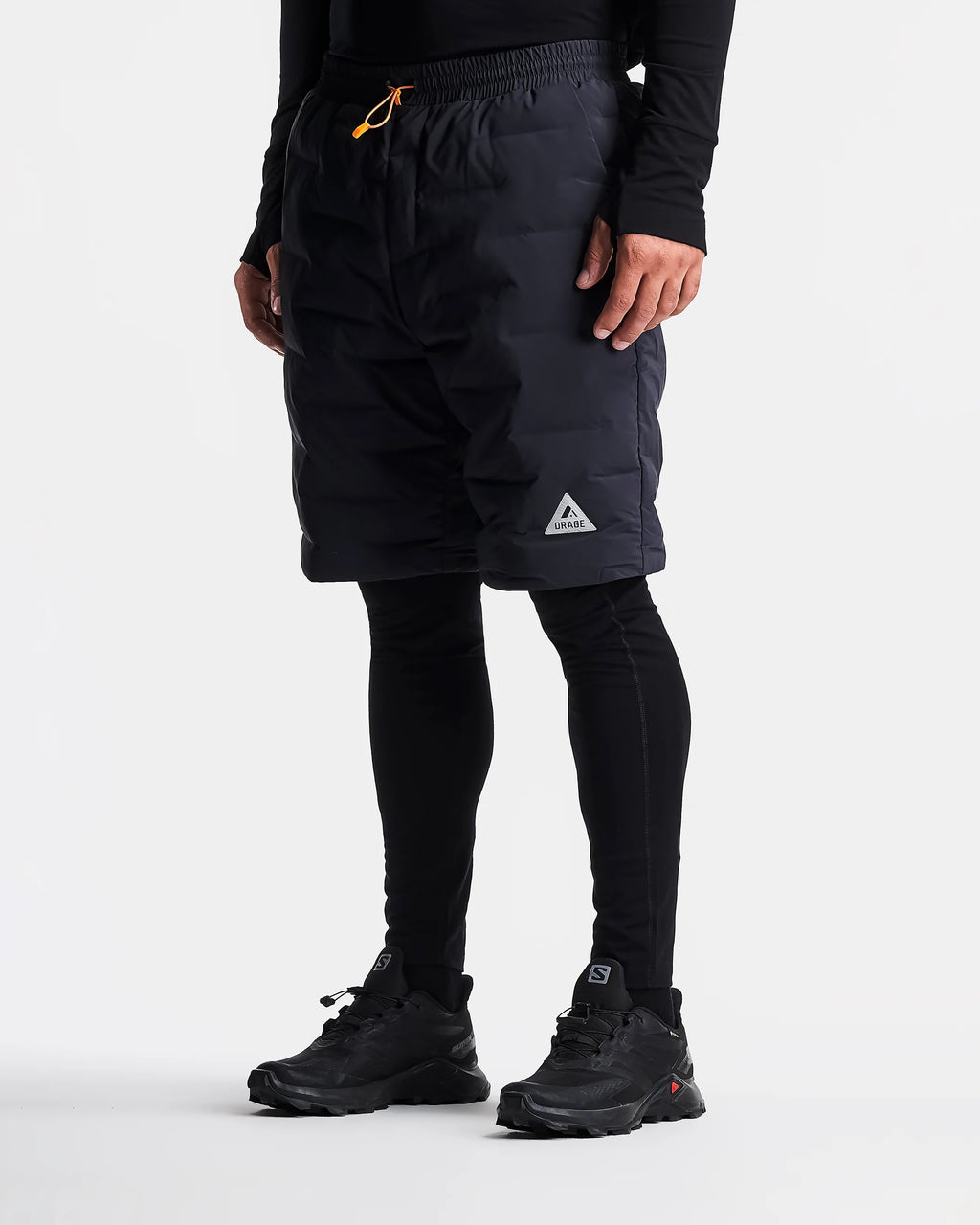 Person wearing black shorts with a brand logo on a white background