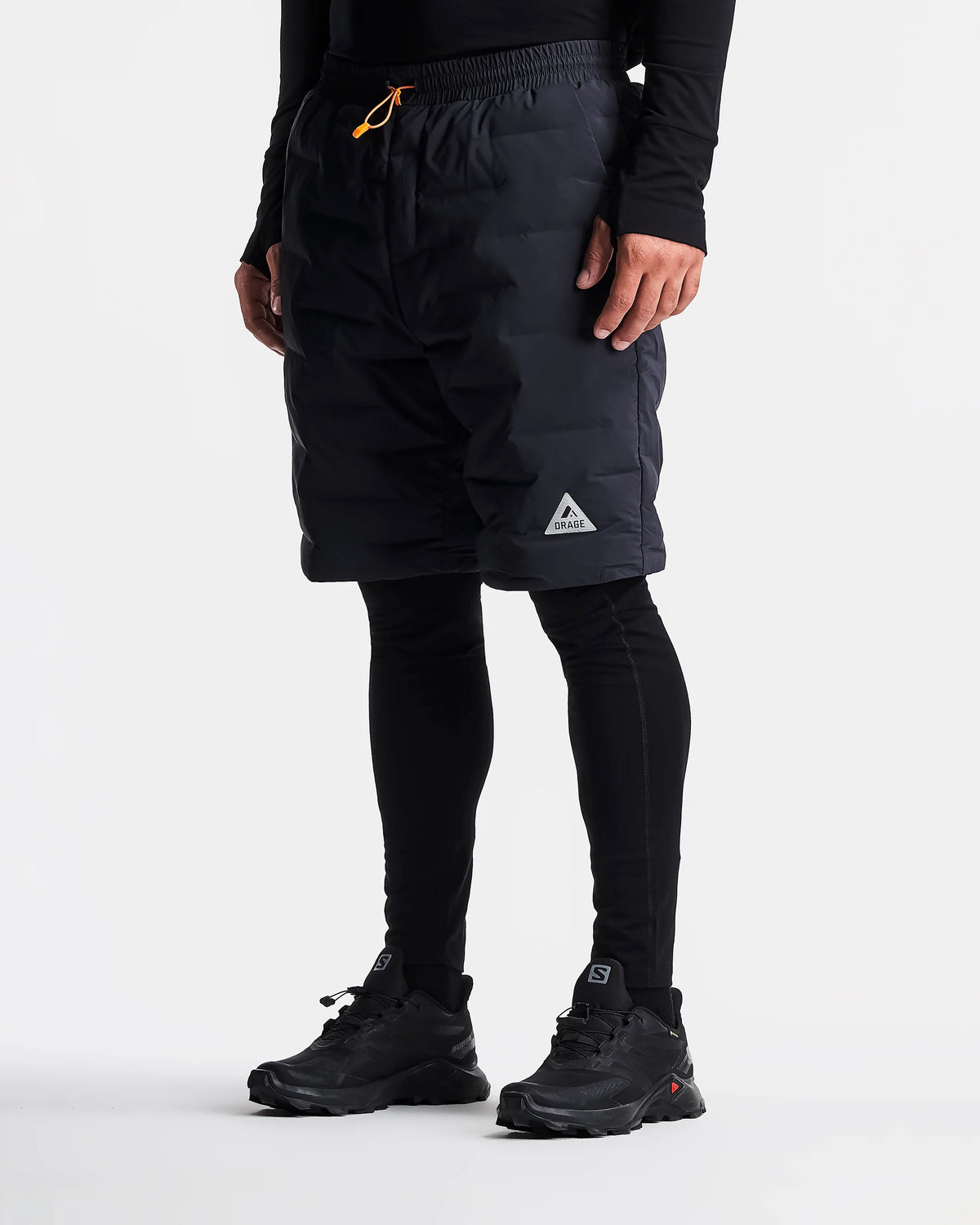 Person wearing black shorts with a brand logo on a white background