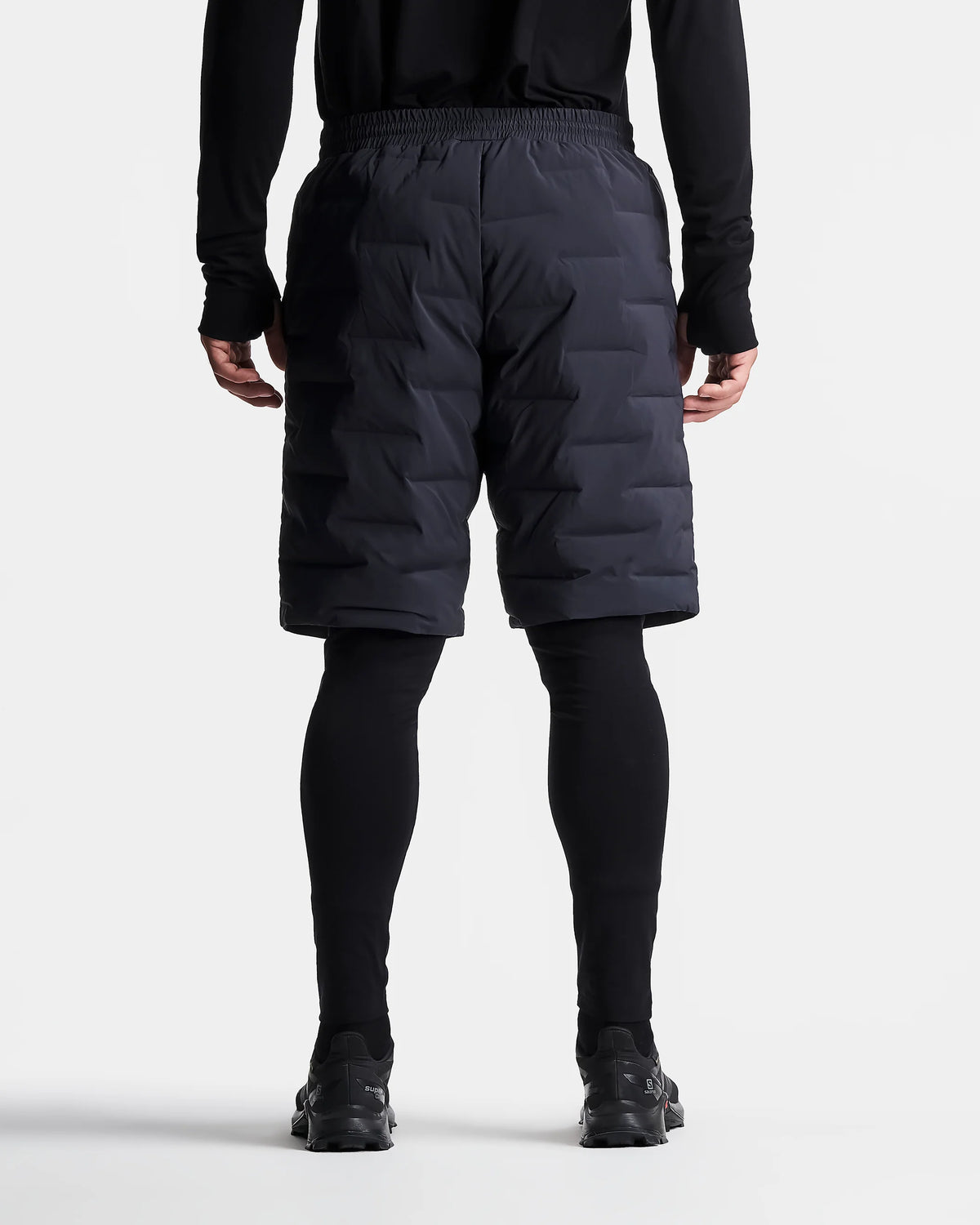 Person wearing black puffer shorts on a white background
