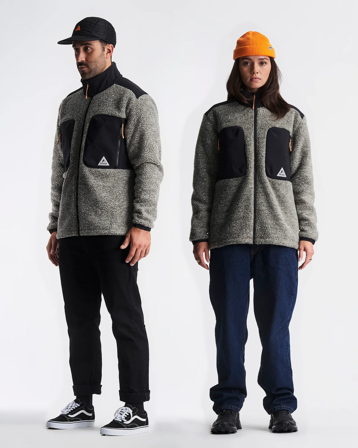 Two people wearing matching gray jackets with black patches on a white background