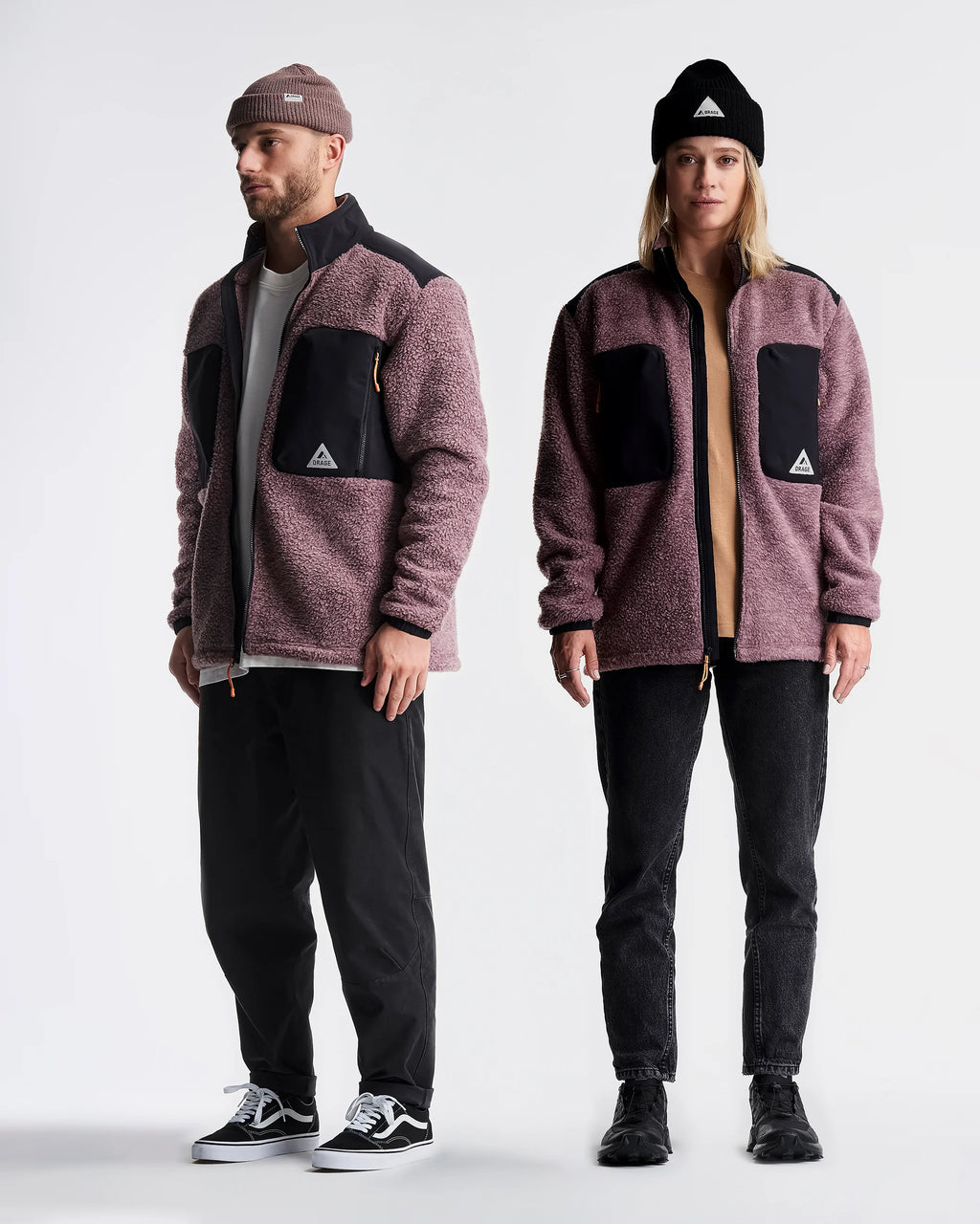 Two people wearing matching jackets and pants on a white background
