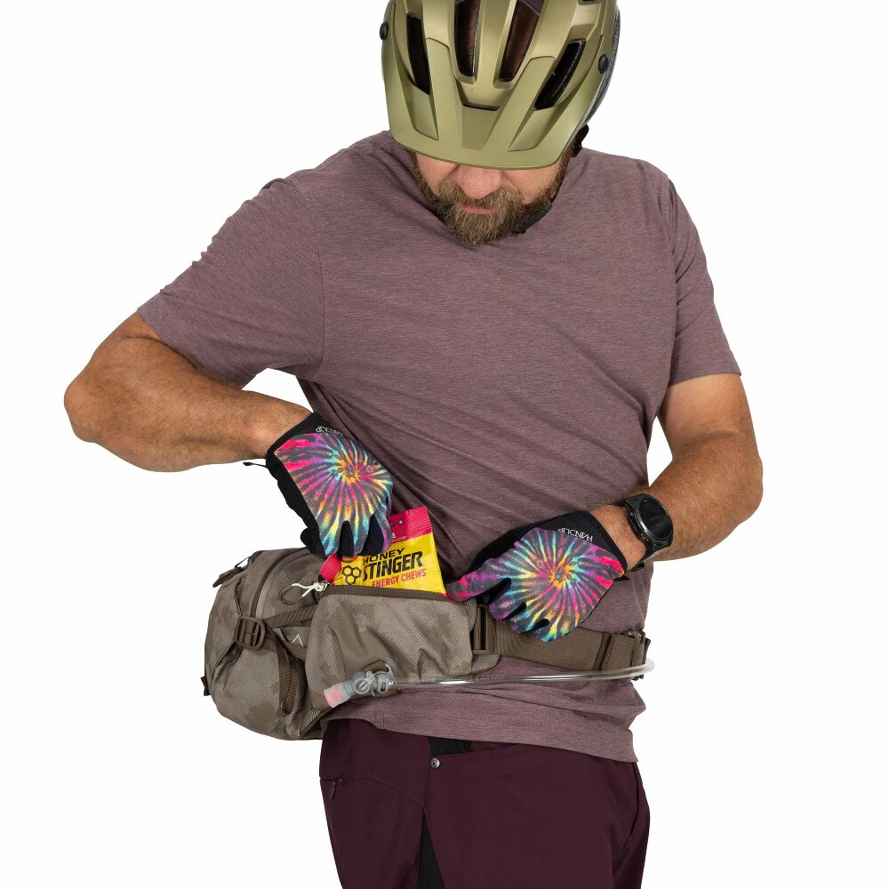 Man wearing a helmet and holding a fanny pack with colorful tie-dye gloves on a white background