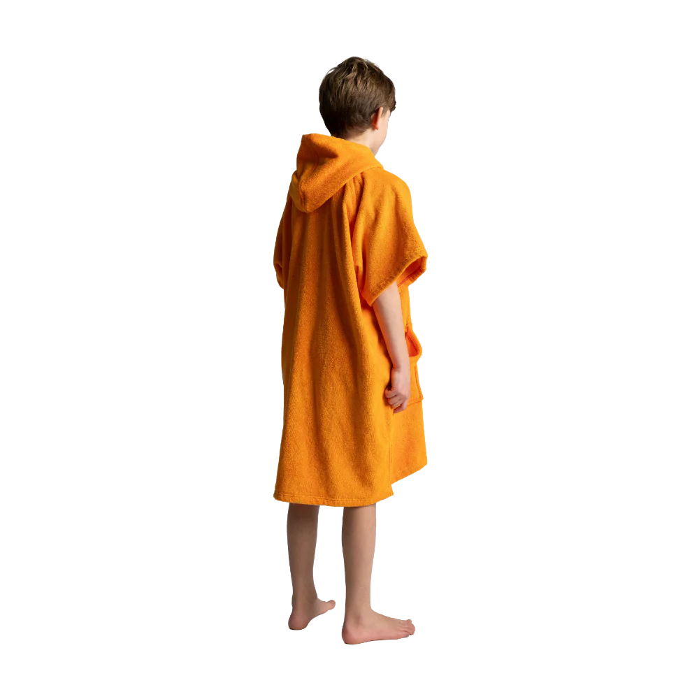 A child standing barefoot from the back, wrapped in a bright orange hooded towel or poncho against a plain white background.