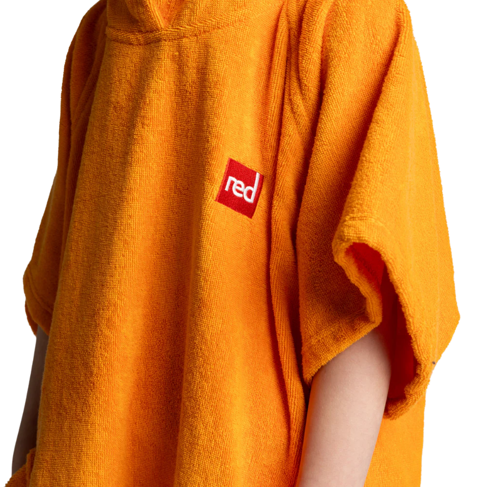 A close-up of a bright orange hooded towel or poncho with a small red square logo containing the word 'red' in white, worn by a person whose arm is visible against a plain white background.