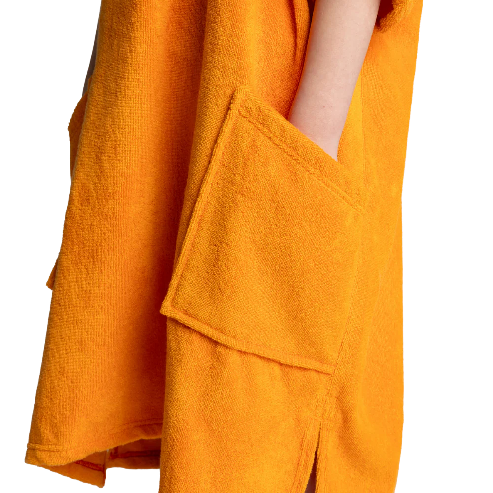 Close-up of a bright orange-yellow towel wrap or robe with a large front pocket and a visible arm tucked into the pocket, shown against a plain white background.
