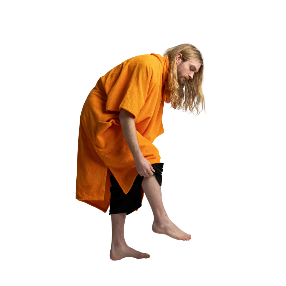A person with long blonde hair and a beard, wearing an oversized bright orange robe over black shorts, shown from the waist up against a plain white background.