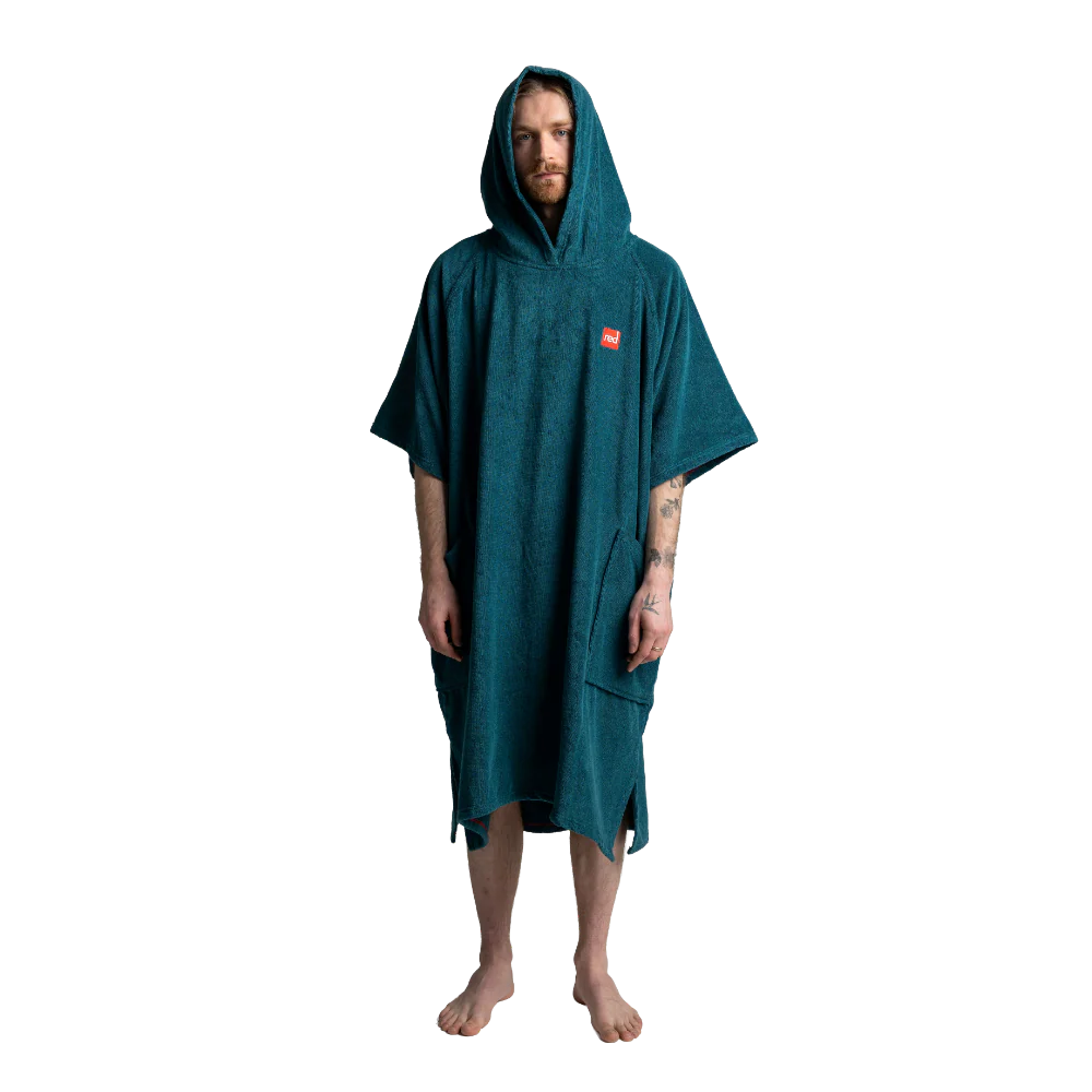 A man wearing a dark teal hooded towel poncho with a small red logo patch on the chest, standing against a solid white background.