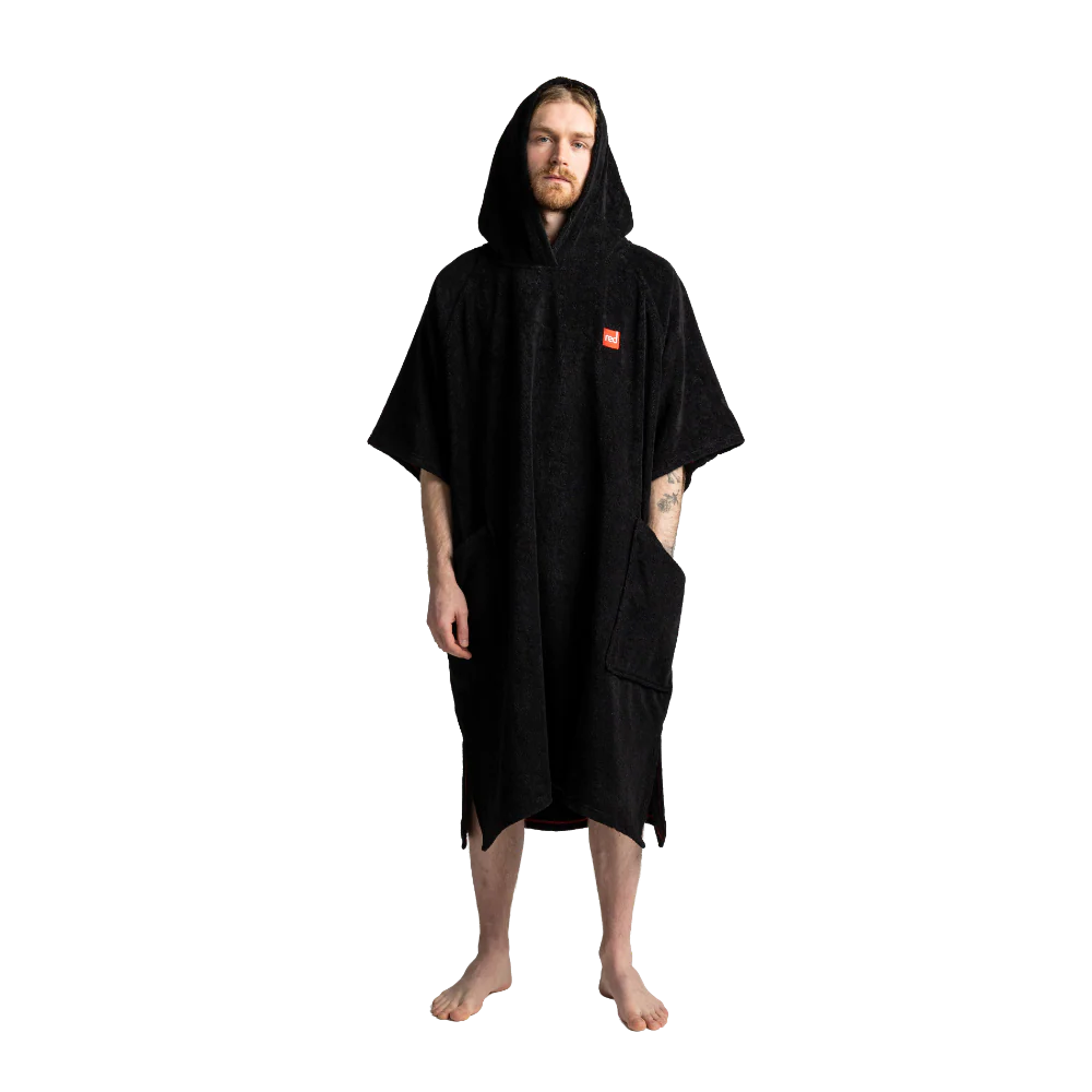 A man wearing a black hooded towel poncho with a small orange square logo on the left chest, standing against a plain white background.