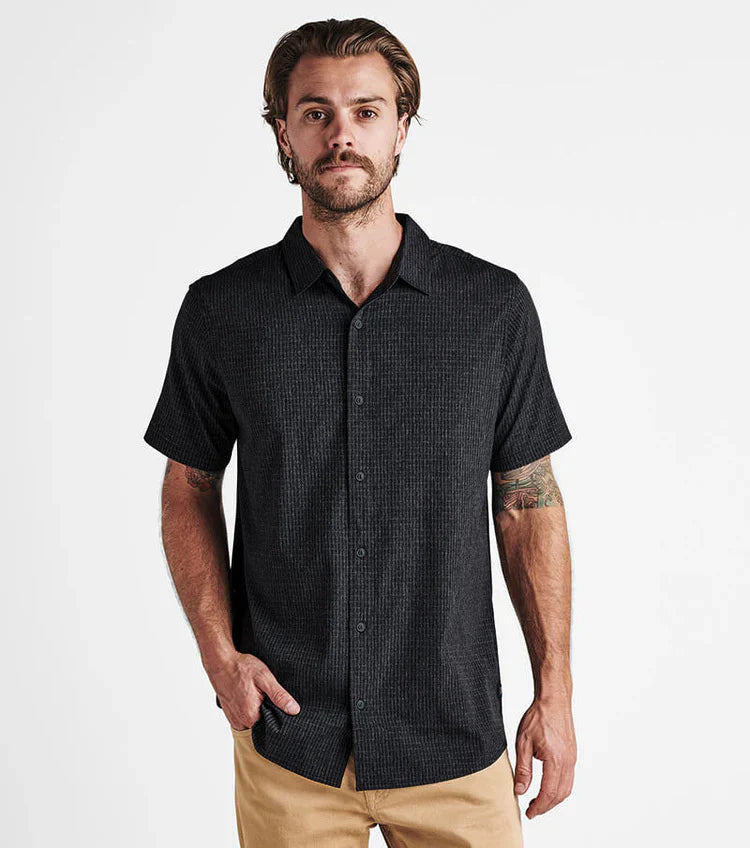 Man wearing a black short-sleeve shirt with a subtle pattern on a white background
