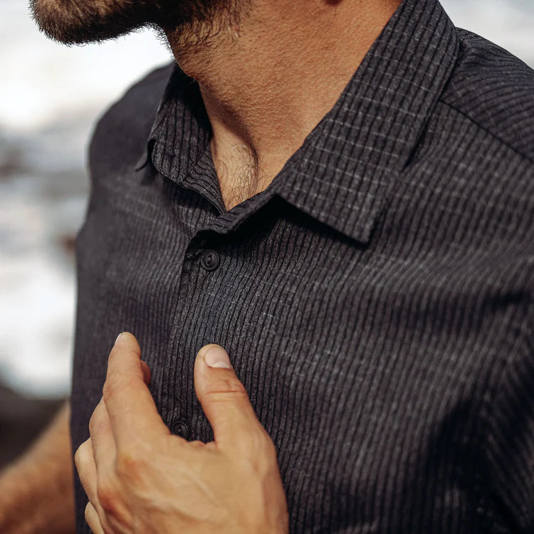 Close-up of a person wearing a dark gray textured shirt with blurred background