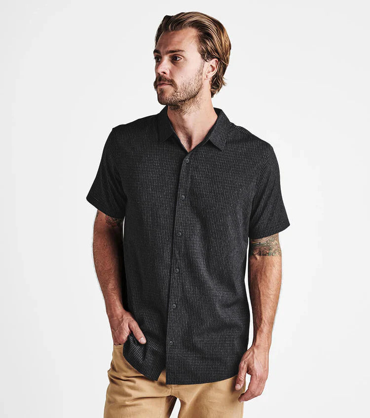 Man wearing a black patterned short-sleeve shirt on a white background