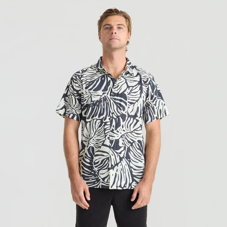 Man wearing a black and white patterned shirt on a light gray background