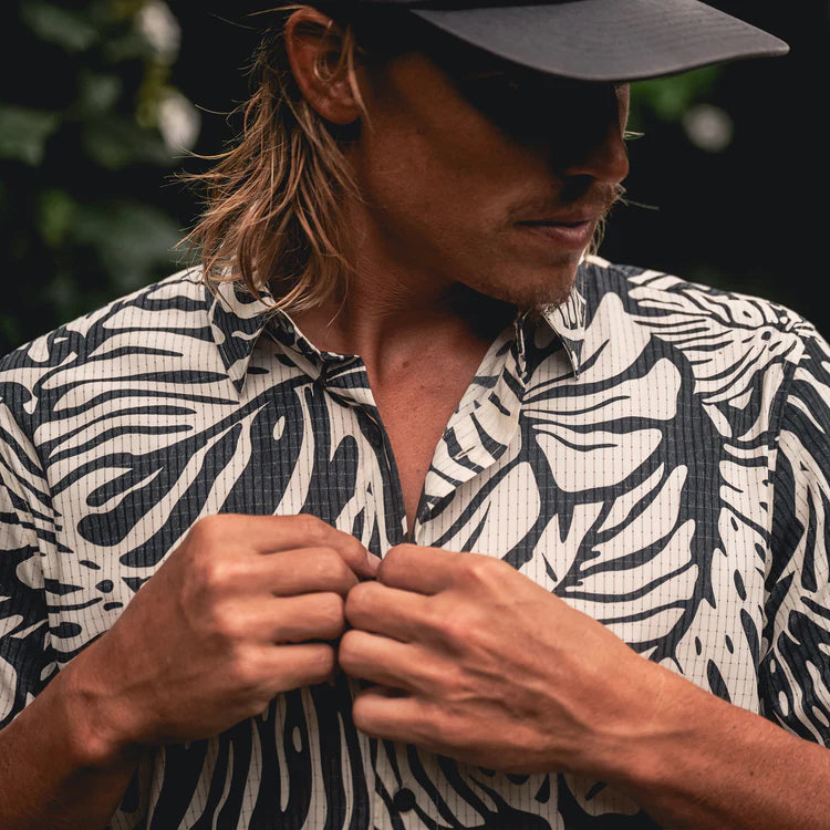 Man wearing a black and white patterned shirt outdoors
