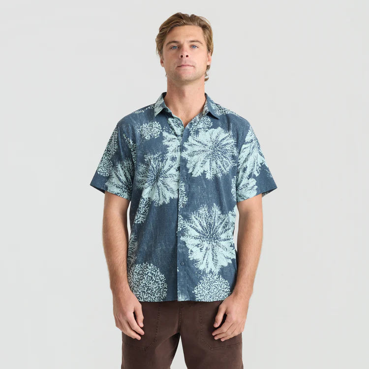 Man wearing a blue floral patterned shirt on a plain background